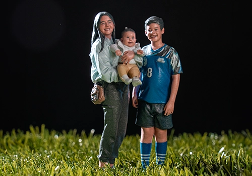 3D-printed replica of a mother holding a baby beside a young soccer player