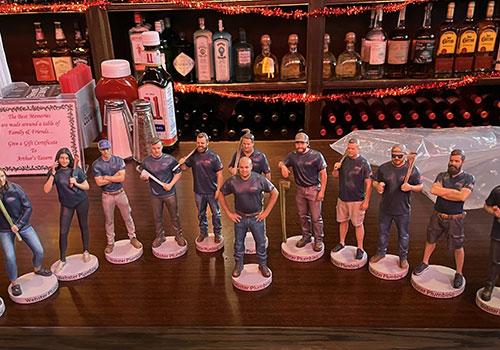 A lineup of 3D-printed corporate team figurines displayed on a bar
